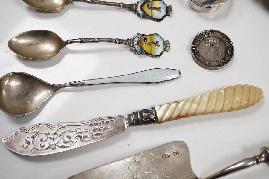 Assorted silverware including a late Victorian mother of pearl handled butter knife, a George V pill box, an Edwardian mustard pot with plated spoon, two enamelled golf related spoons, a rifle shooting related spoon, six